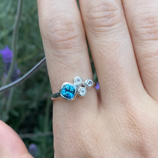 Blue and white topaz cluster ring shown on hand model